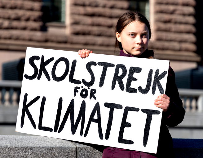 Greta Thunberg segura um cartaz onde lê-se greve escolar pelo clima